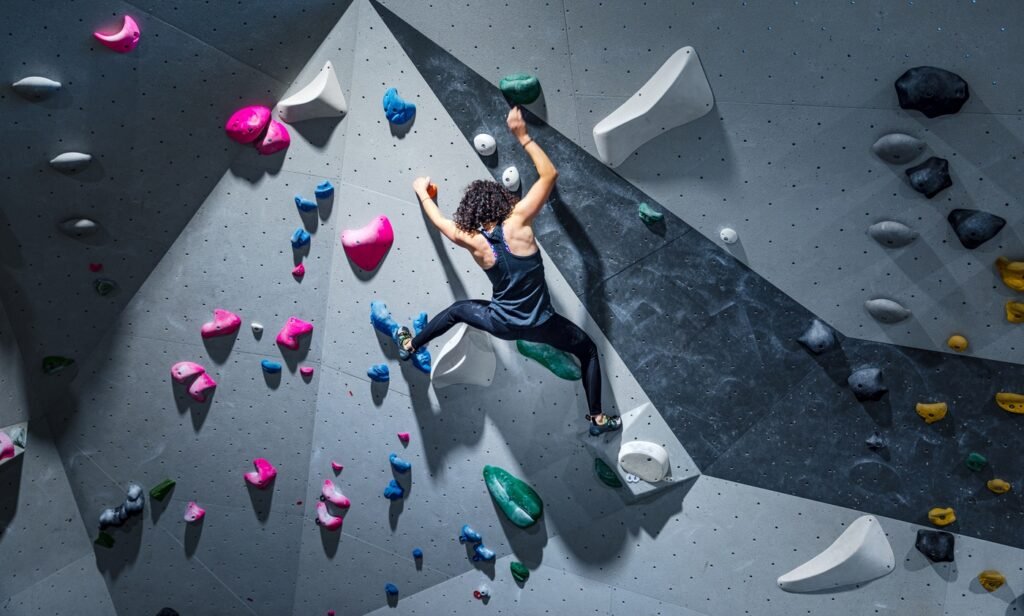 Climber scaling bouldering wall representing leadership development through challenge